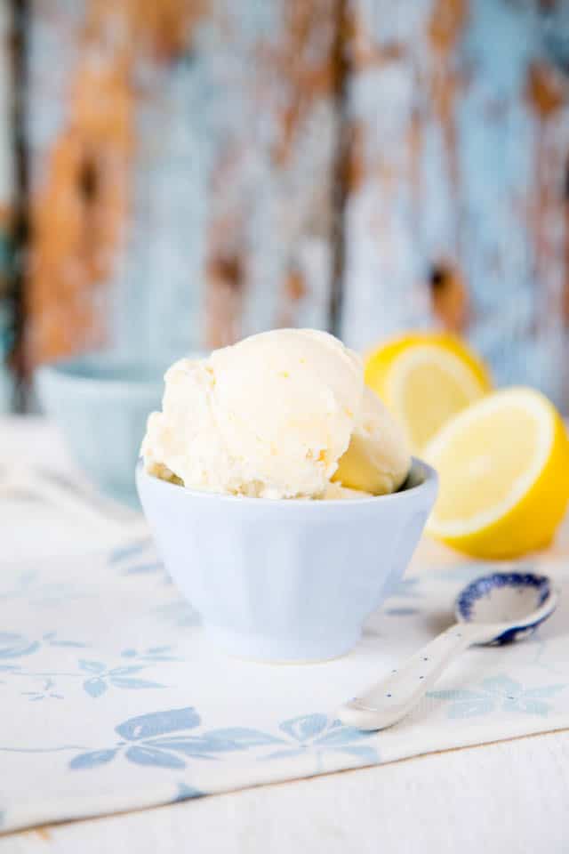 Close up of lemon curd ice cream in a white bowl against a blue rusted background
