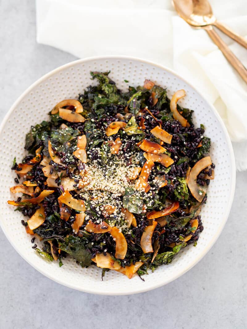 Overhead view of crispy kale and black rice salad in a white bowl.