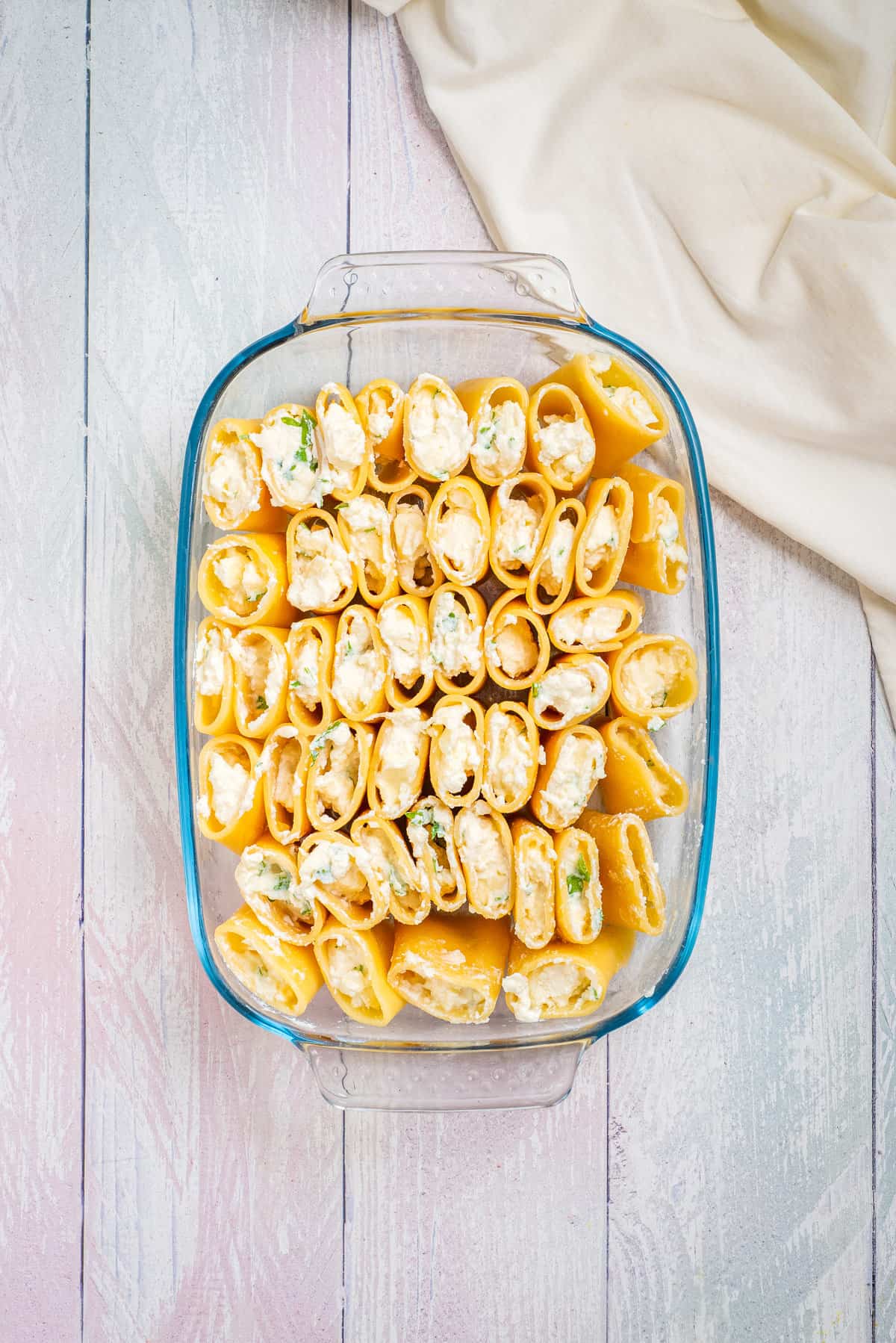 Overhead view of a baking dish with arranged pasta filled with cheese mixture.