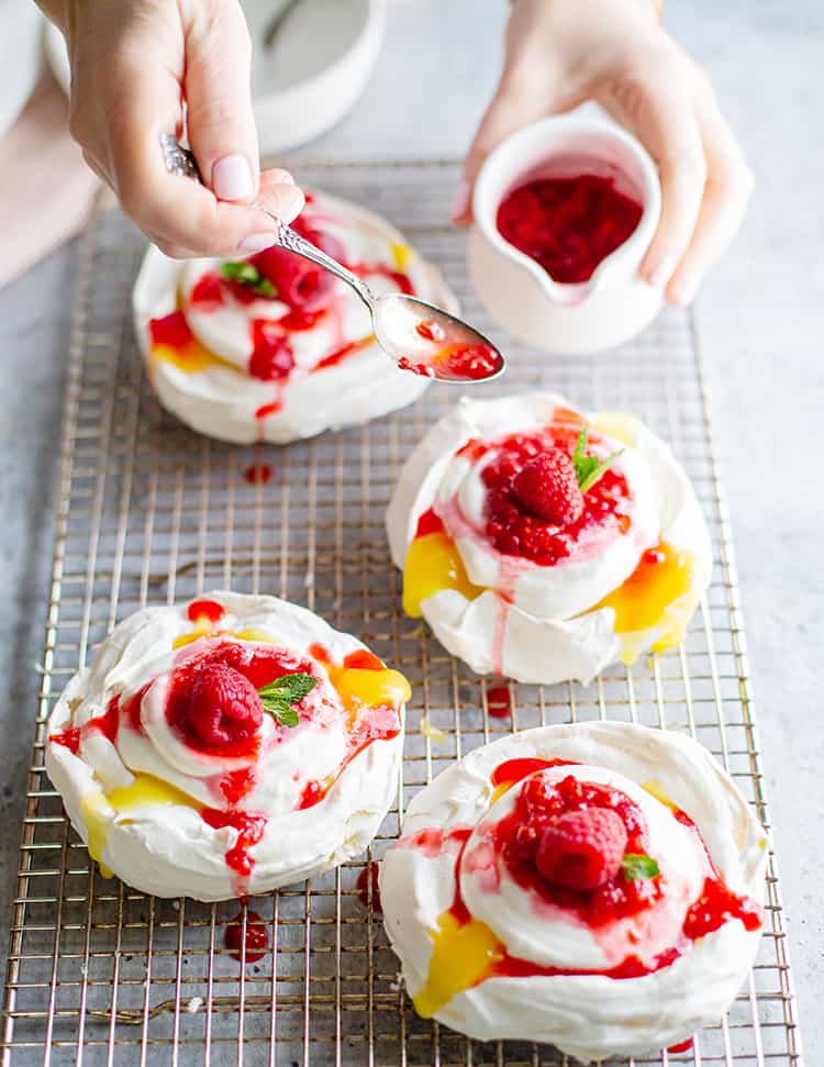 An overhead view of lemon curd pavlova placed on a wired rack with a raspberry on top.