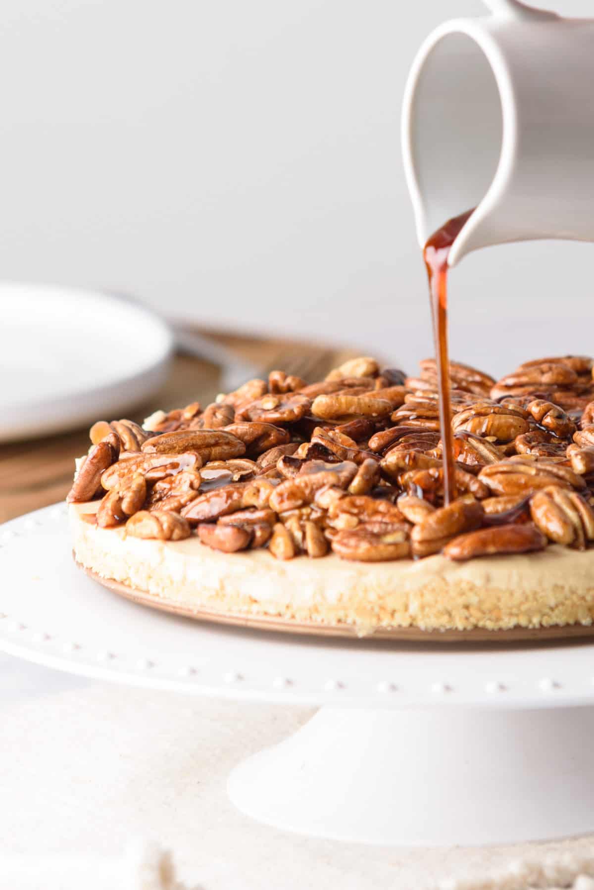 Caramel being poured over the full pecan pie cheesecake.