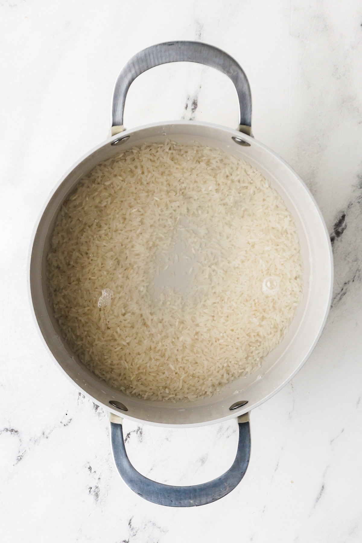 An overhead image of cooking rice with water in a saucepan.