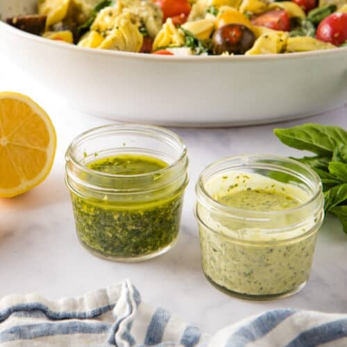 Close up shot of two jars with pesto vinaigrette and creamy dressing side by side.