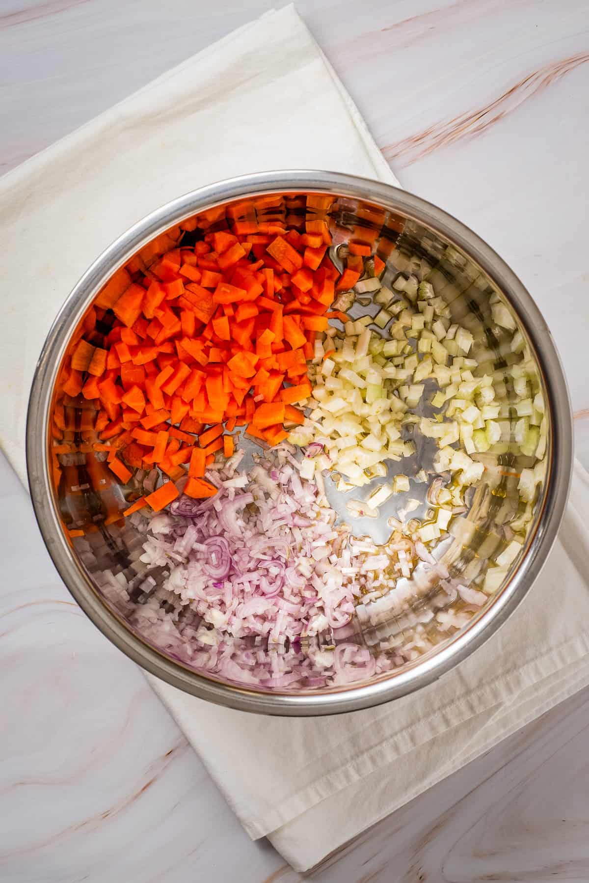 Overhead view of carrots, garlic and onion in the pot of an Instant Pot. 