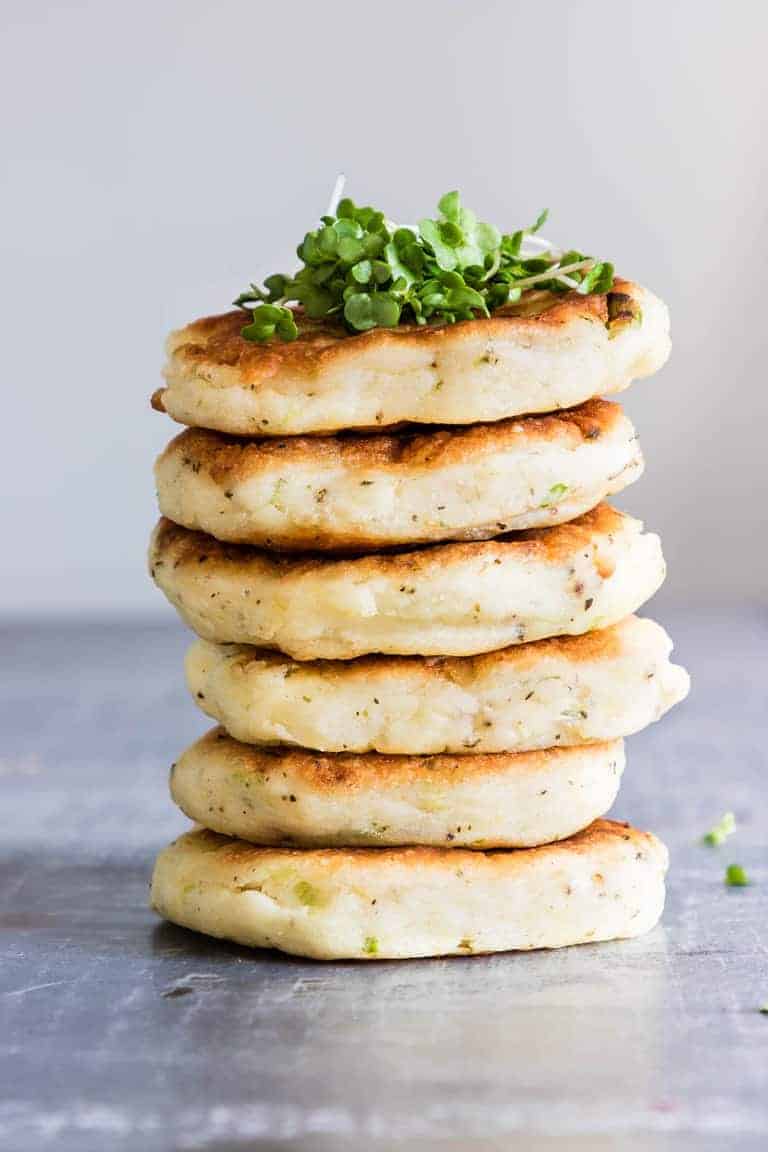 A close-up view of a stack of six potato pancakes with leftover mashed potatoes.
