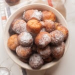 Bowl of golden Nigerian puff puff dusted with powdered sugar.