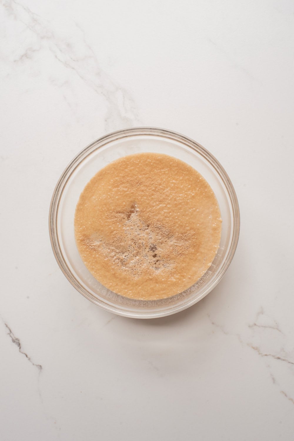 Foamy activated yeast mixture in a glass bowl.