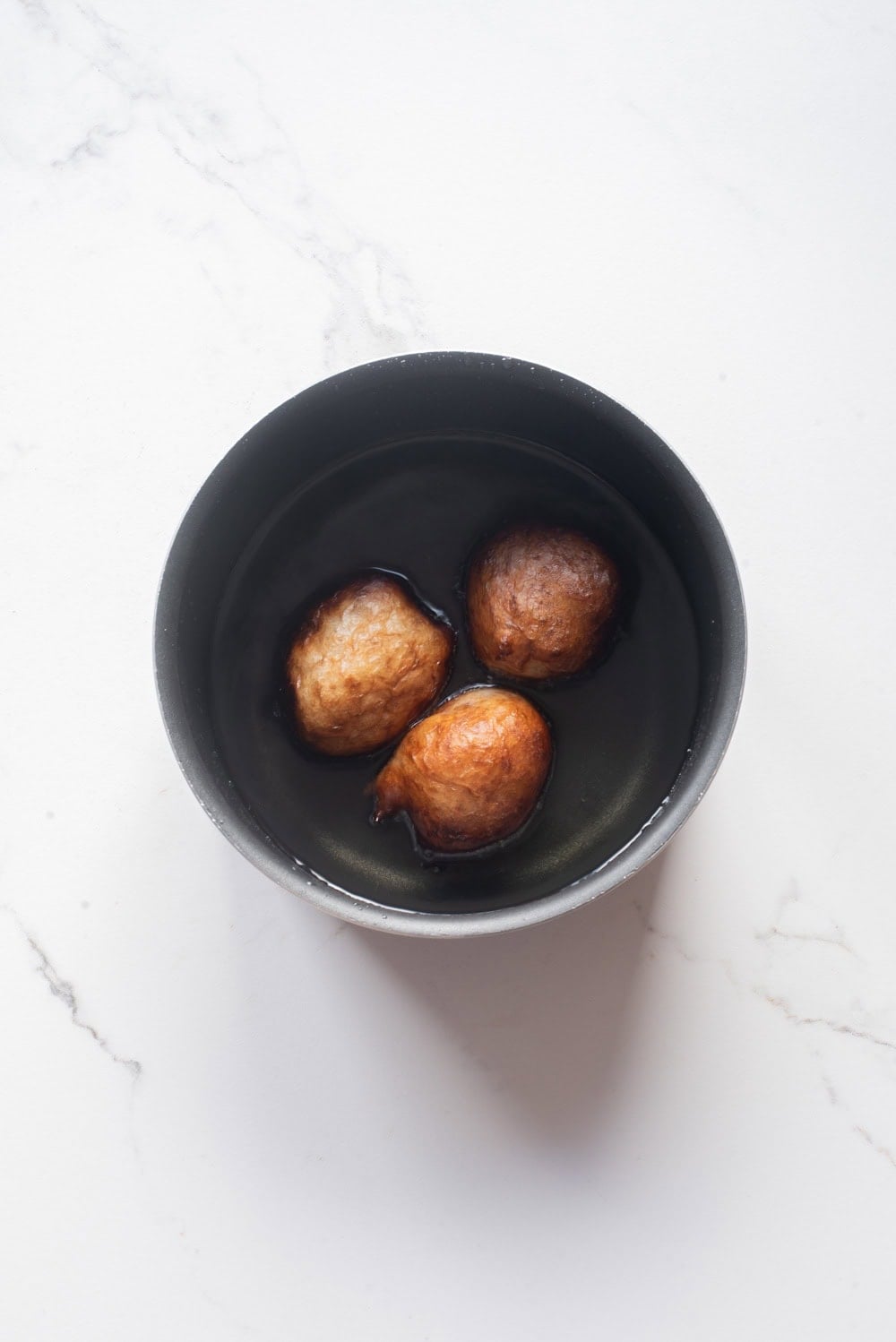 Nigerian puff puff balls frying in hot oil in a deep pot.
