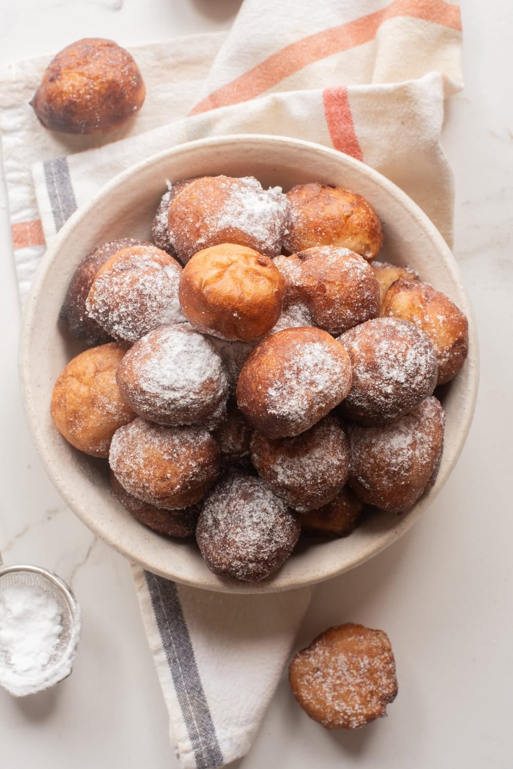 Bowl of Nigerian puff puff dusted with powdered sugar, ready to serve.
