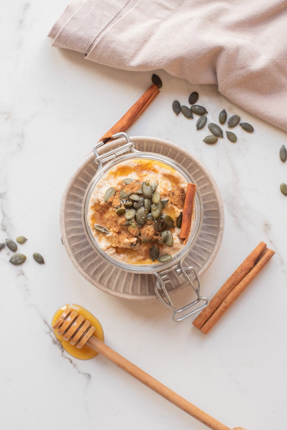 Overhead image of pumpkin pie overnight oats with toppings in a jar.