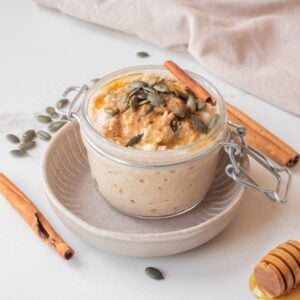 Close-up image of pumpkin pie overnight oats with toppings in a jar.