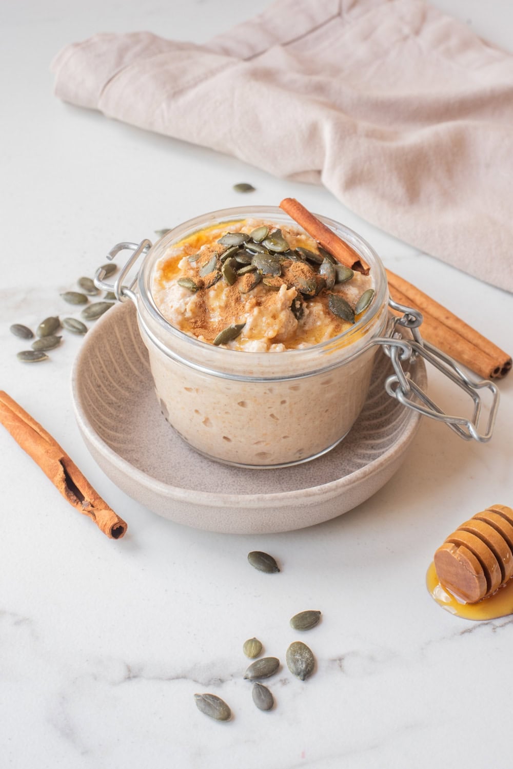 Close-up image of pumpkin pie overnight oats with toppings in a jar.