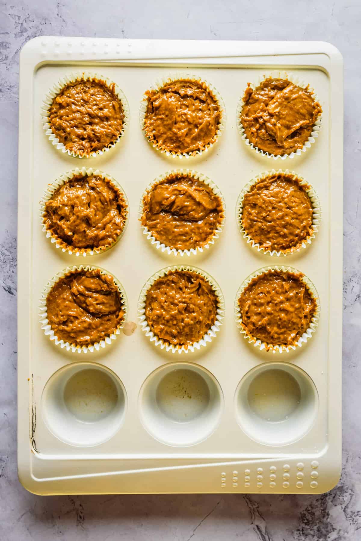 Overhead view of muffin tin filled with batter. 