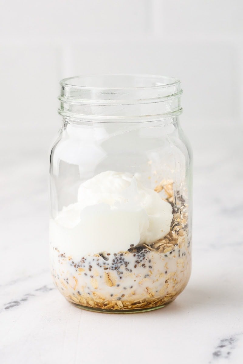 Overnight oats ingredients added to a mason jar before mixing and refrigerating.
