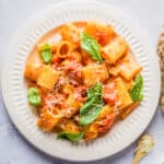 Overhead view of rigatoni arrabbiata placed on a white plate with fresh parsley on top.