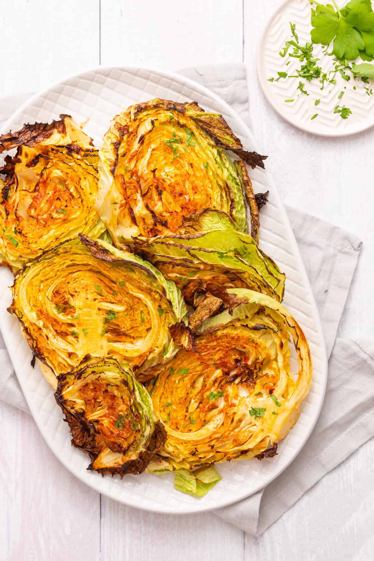 An overhead image of roasted cabbage steaks on a serving plate.