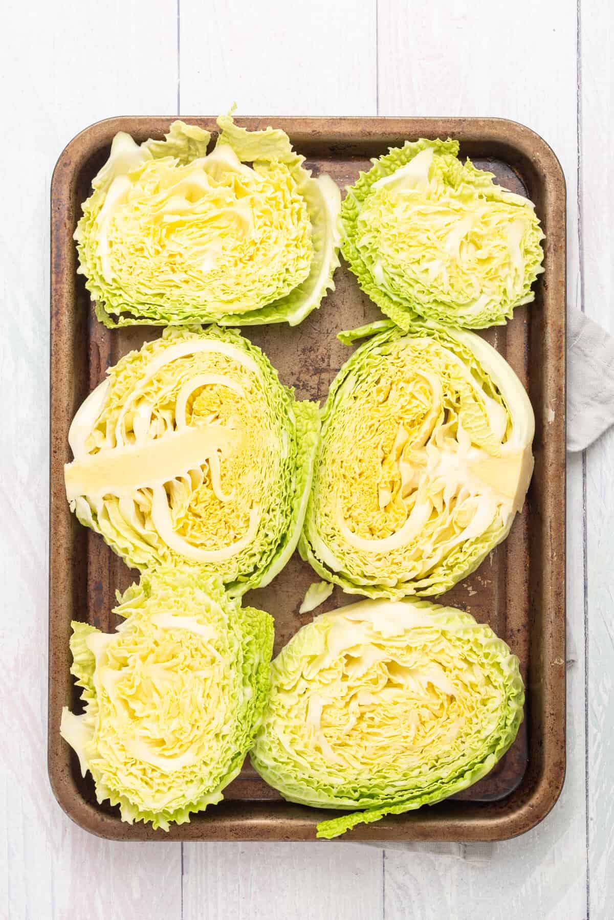 An image of cabbage steaks arranged in a baking sheet.