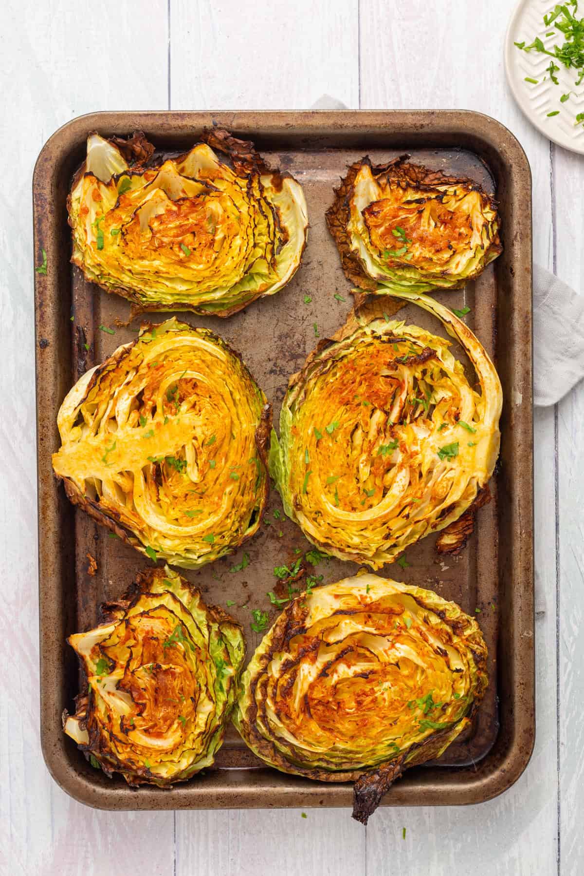 An overhead image of roasted cabbage steaks on a baking sheet.