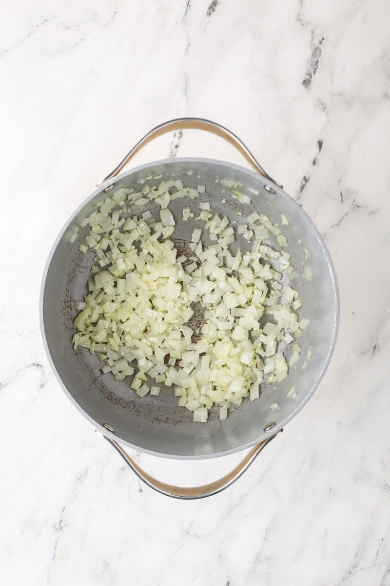 Diced yellow onion sautéing in a pot for roasted honeynut squash soup.