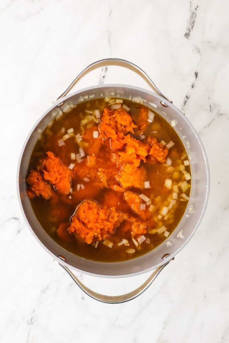 Roasted honeynut squash, broth, onion, and seasonings simmering in a pot.
