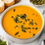 Bowl of roasted honeynut squash soup topped with crispy sage and pepitas.