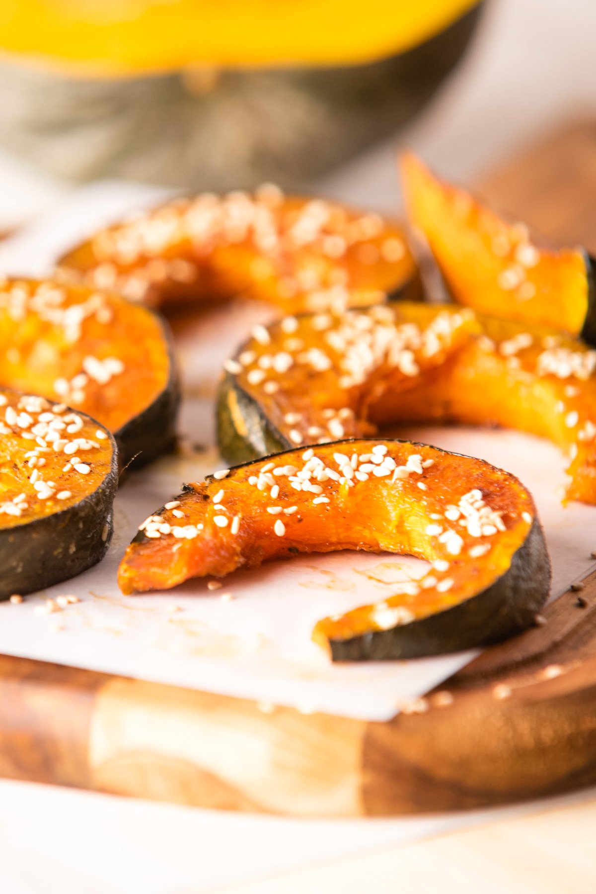 Close up of slices of kabocha squash sprinkled with sesame seeds.