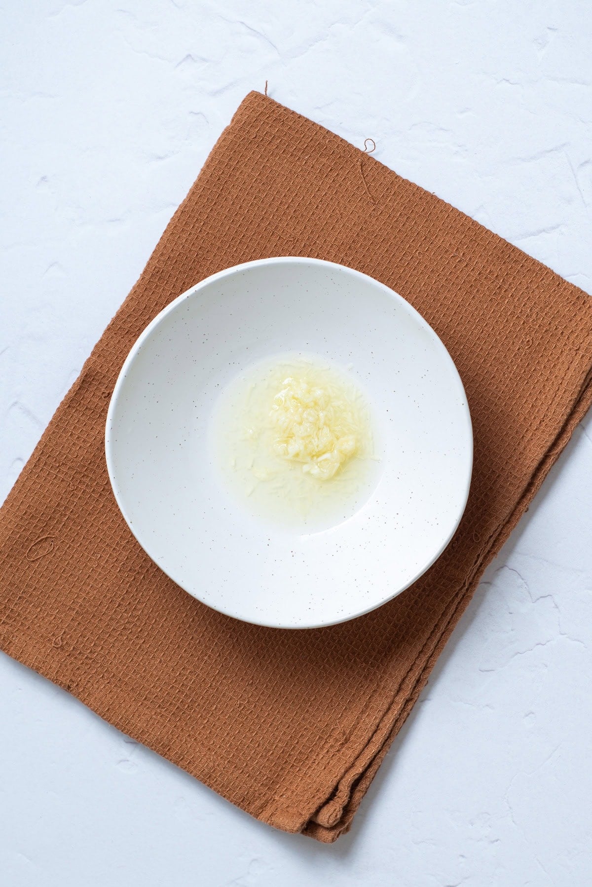 An overhead image of starting the garlic in a bowl.