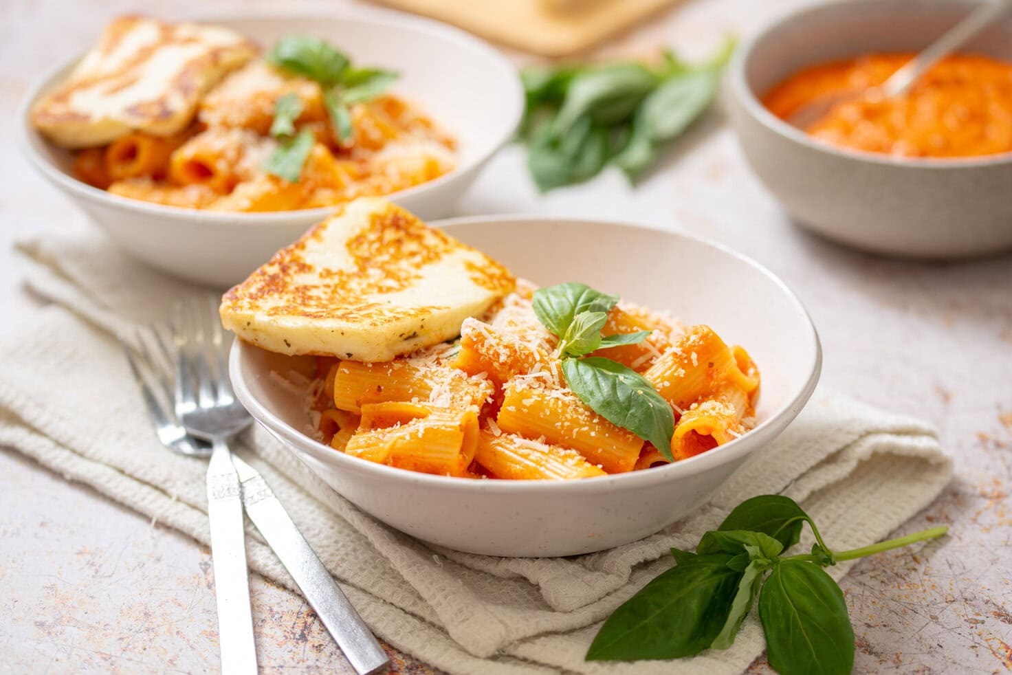 Romesco pasta with seared halloumi in a white bowl