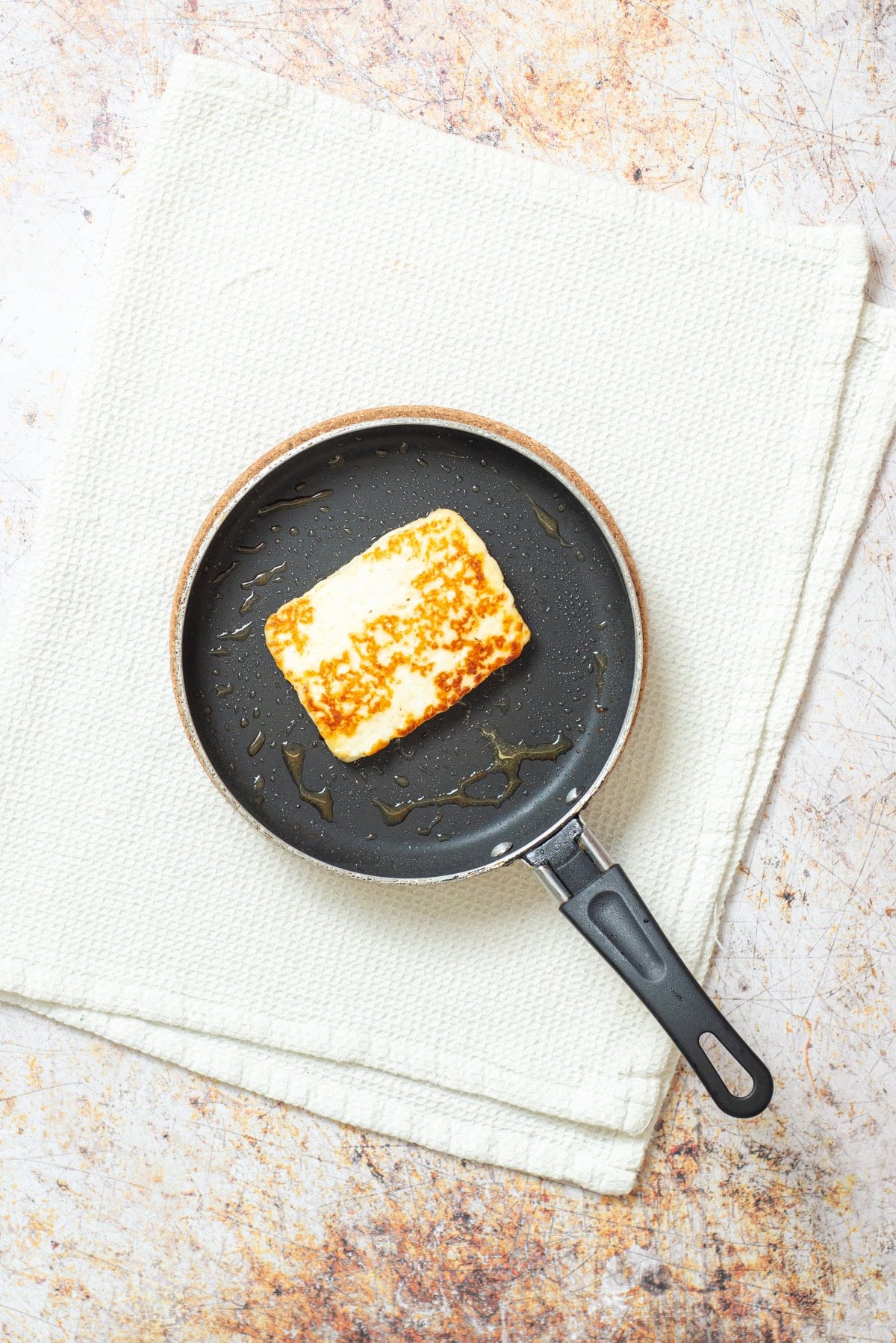 Halloumi cheese searing in a skillet until golden brown.