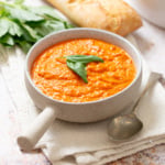 Bowl of homemade romesco sauce garnished with fresh basil and served with crusty bread.