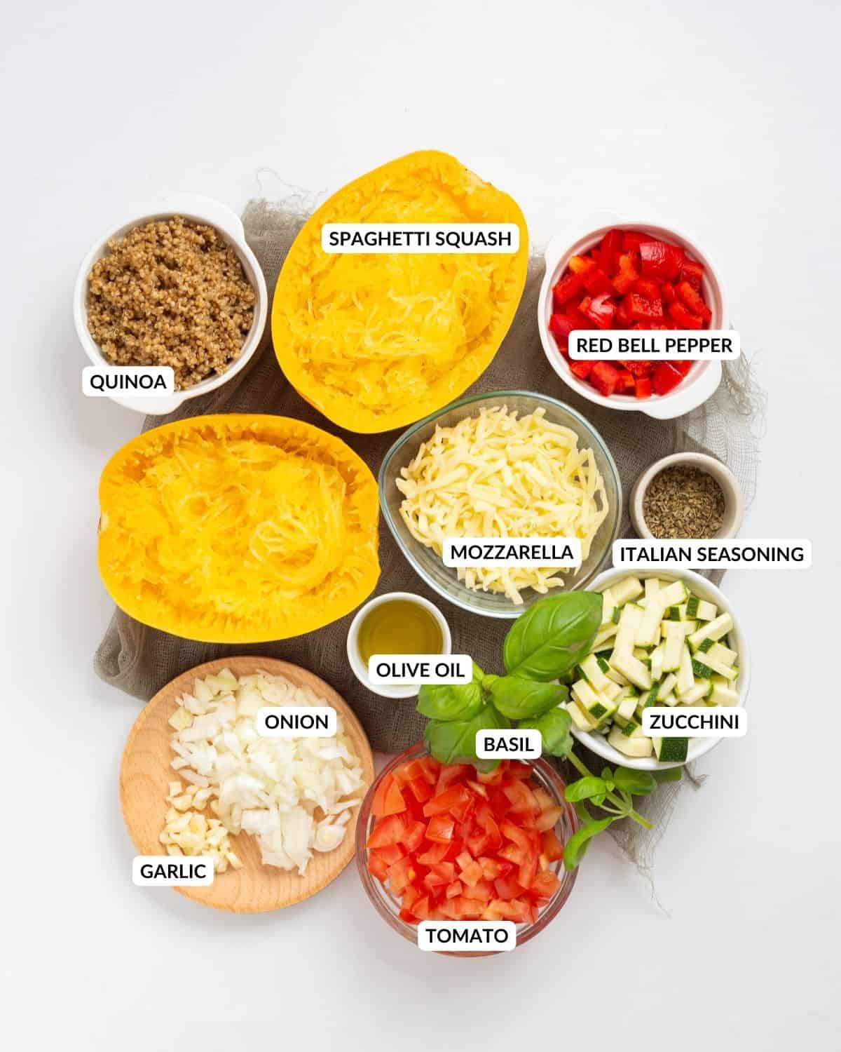 An overhead image of the ingredients of stuffed spaghetti squash laid out on a white countertop.