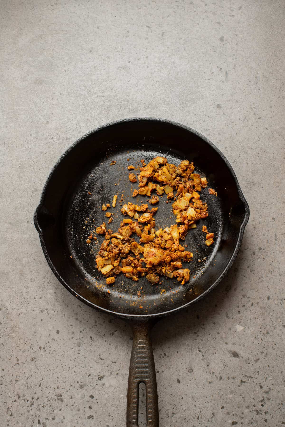 An overhead image of adding the spices to the skillet.