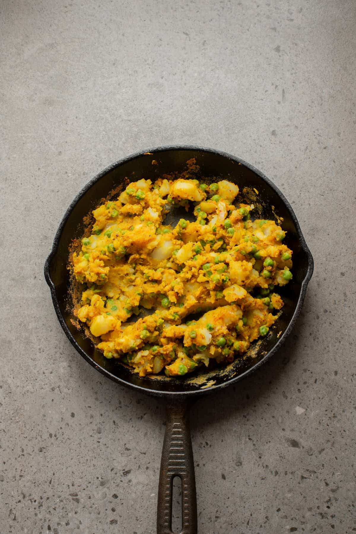 An overhead image of adding potatoes and peas to the mixture.