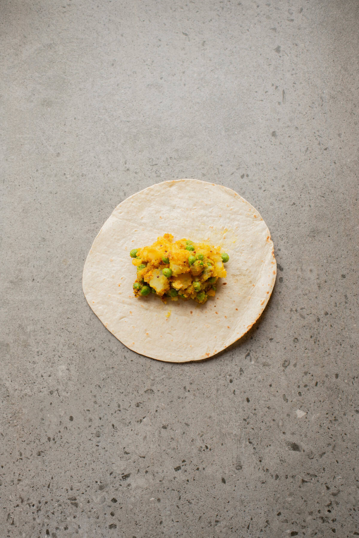 An overhead image of filling a tortilla with the samosa filling.