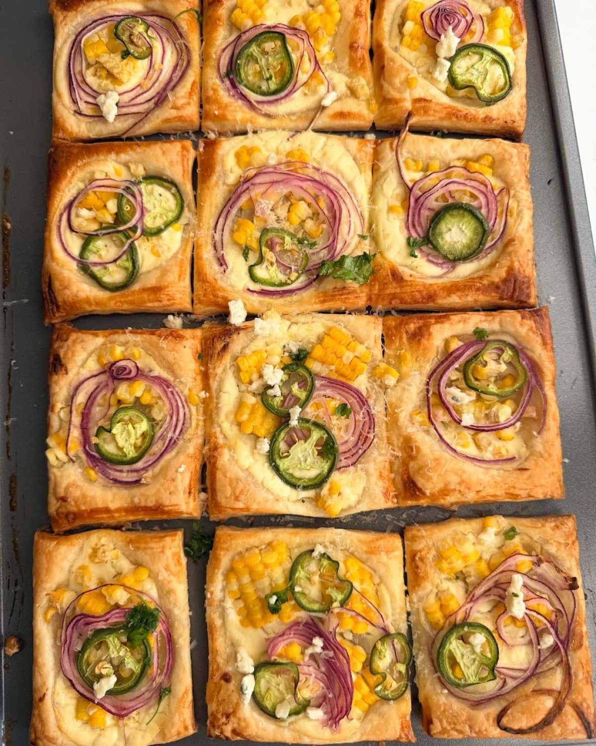 Overhead image of savory corn tart on a dark baking sheet.