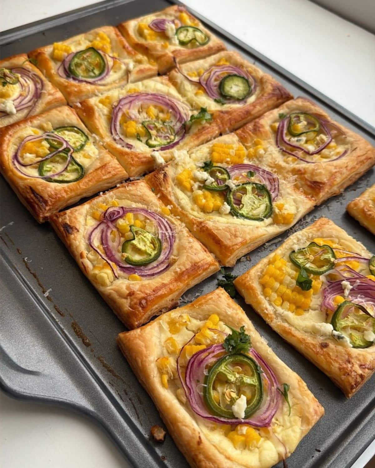 Savory corn tart on a dark baking sheet.