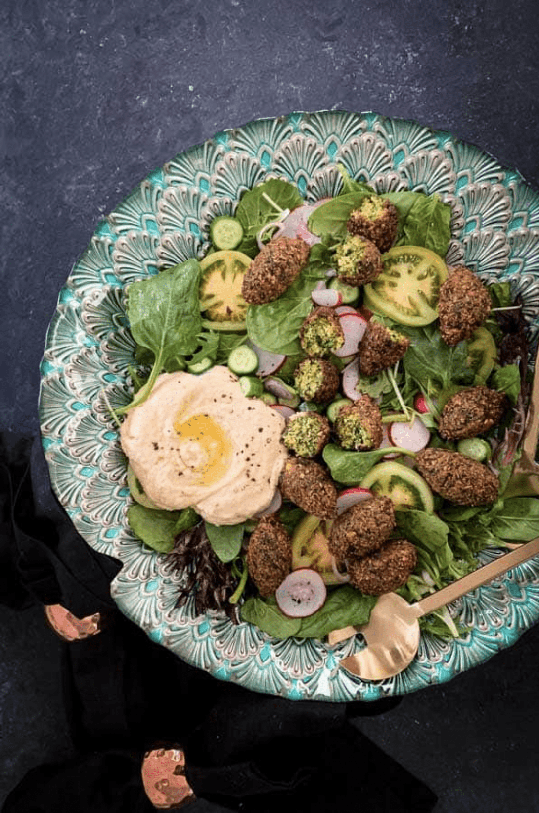 An overhead shot of vegan falafel salad with gold spoon served in a green platter.