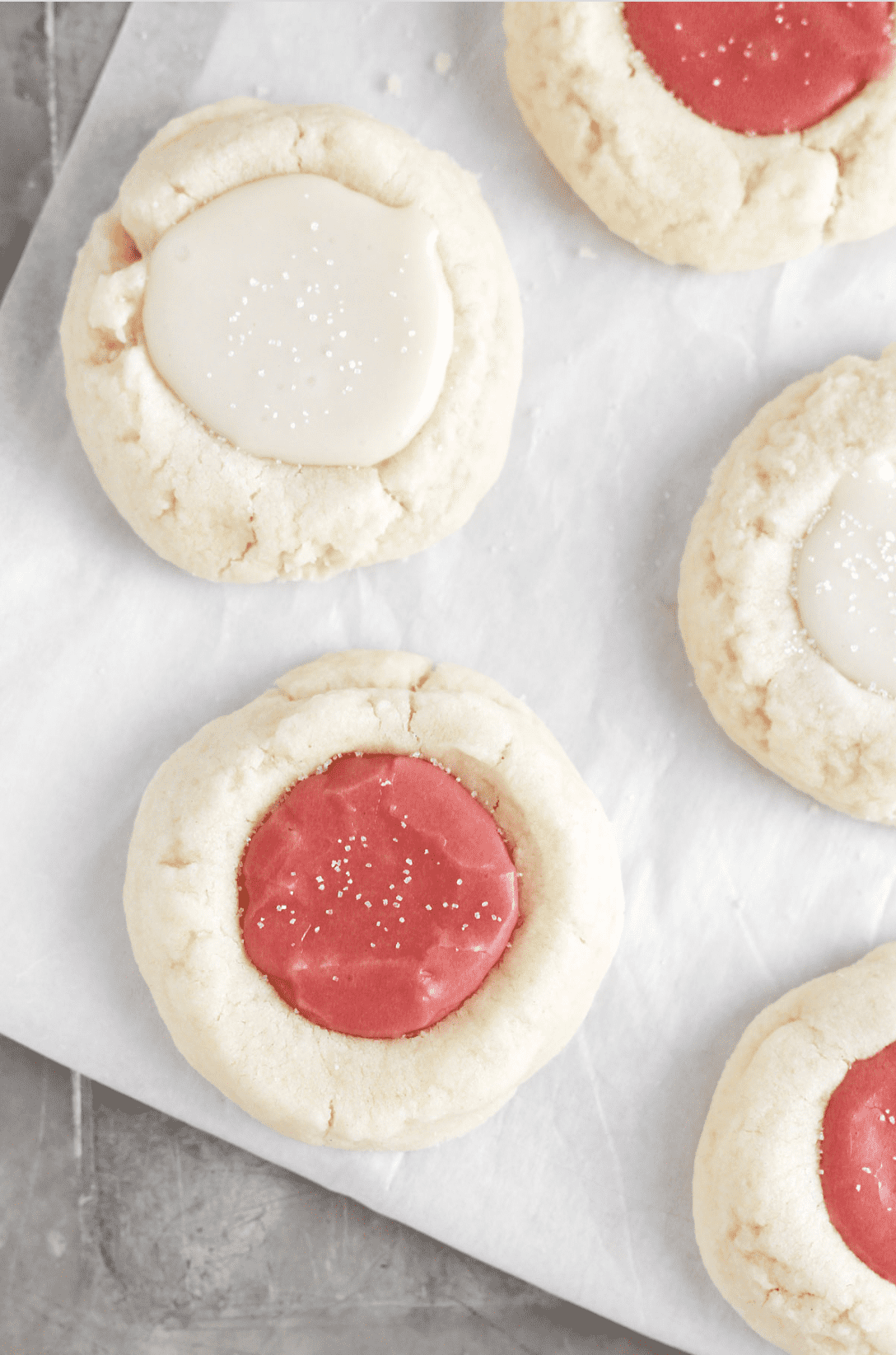 An overhead view of vegan thumbprint cookies with white and red icing in the center.