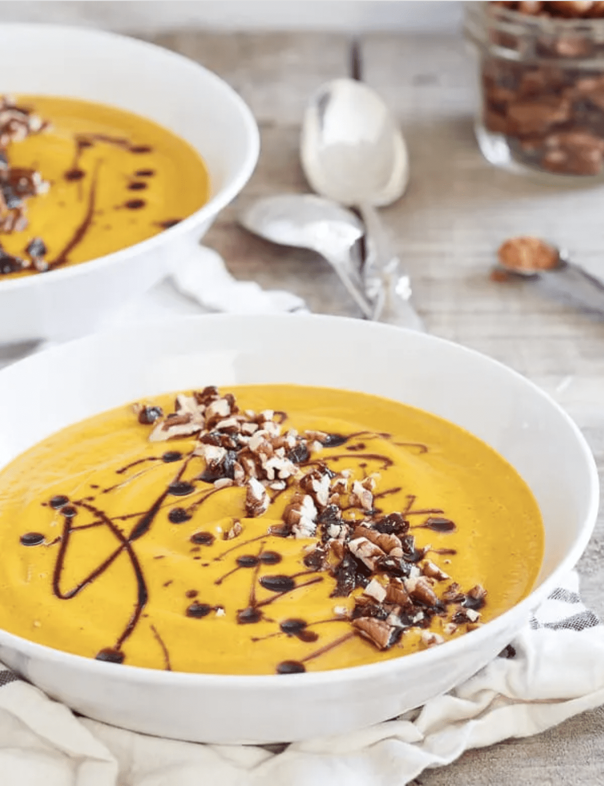 A straight view of two bowls full of creamy kabocha squash soup.