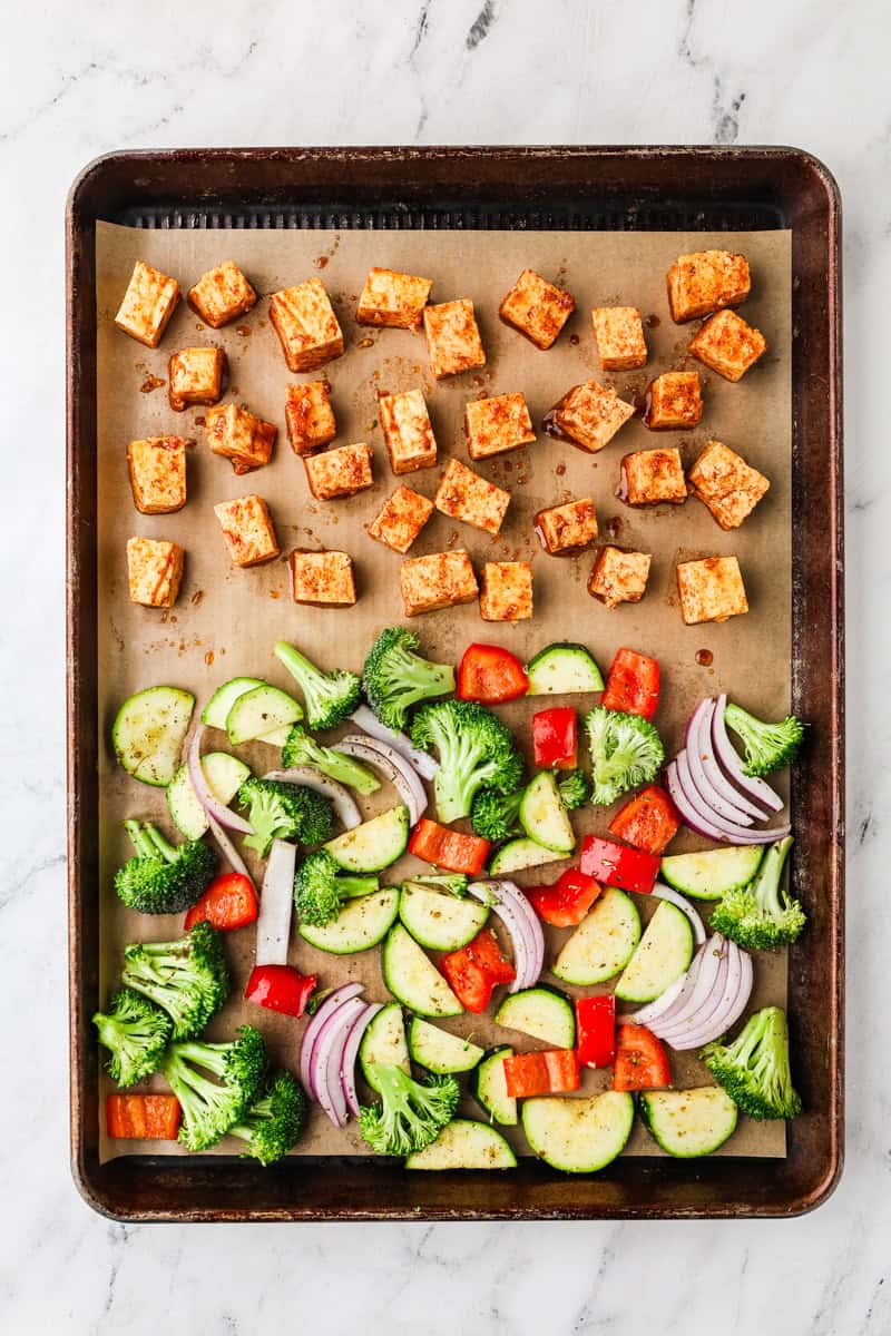 An overhead image of arranging tofu and veggies on a sheetpan.