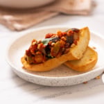 A close up image of Sicilian caponata served on a toasted bread.