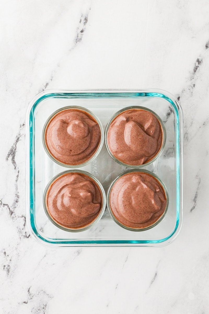 An overhead image of dividing the chocolate mousse to cups.