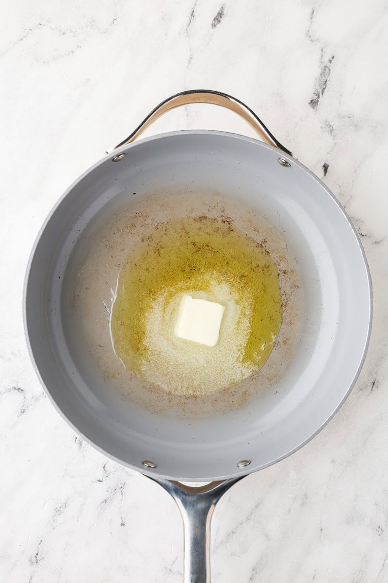 Butter melting into olive oil in a large skillet over medium-high heat.
