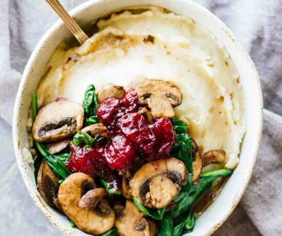 An overhead view of slow cooker mashed potatoes and cranberry mushroom sauce in a white bowl.