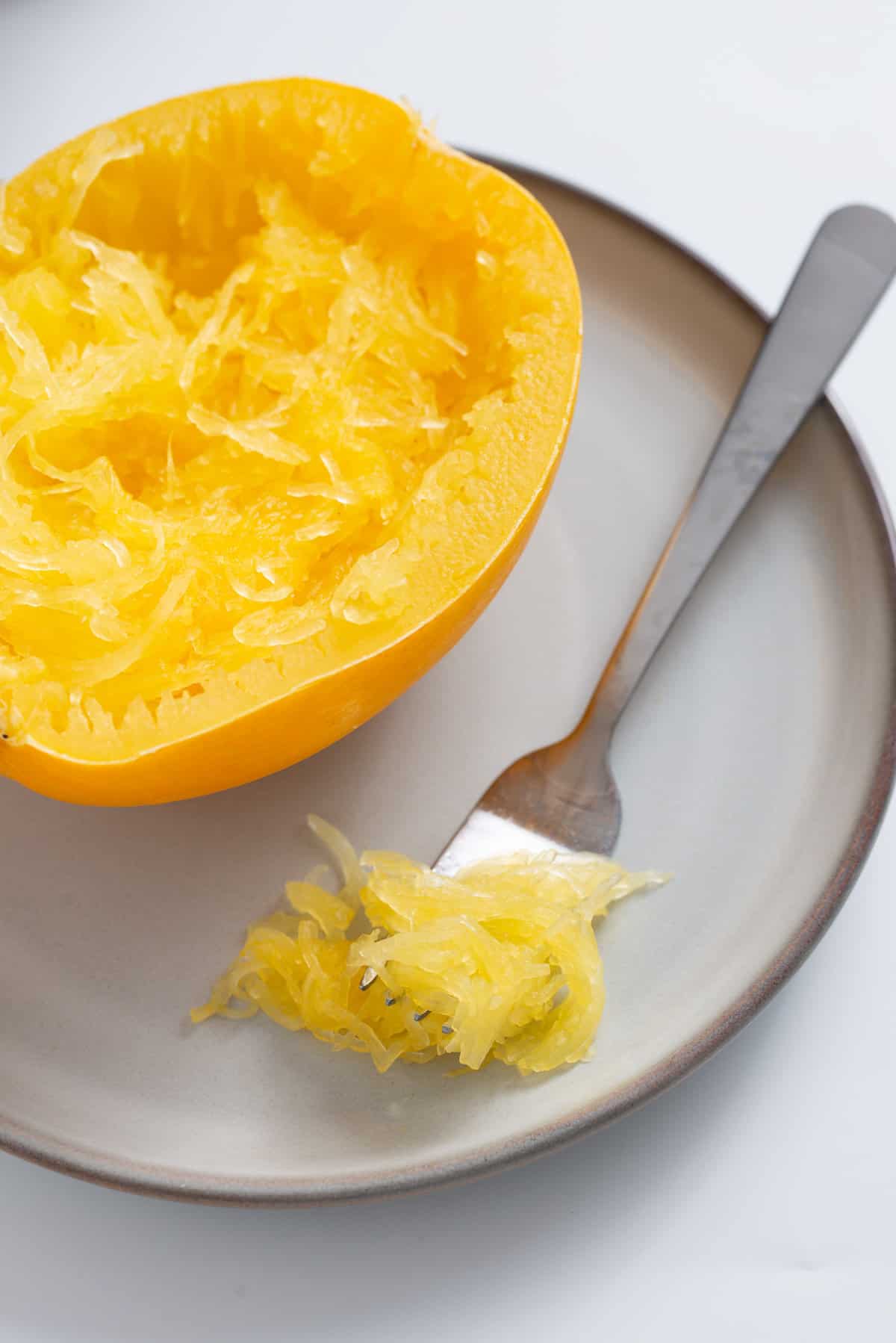 An image of cooked spaghetti squash with a fork with spaghetti strands on the side.