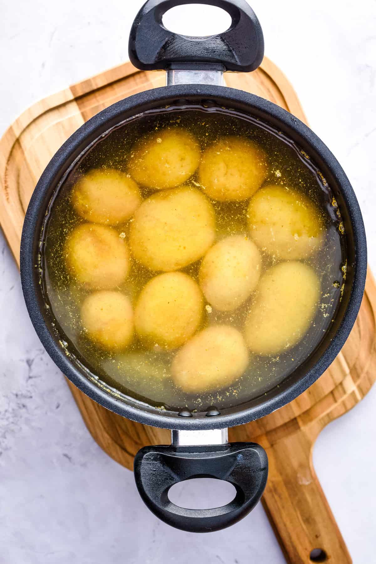 Overhead view of potatoes boiling in a pot. 