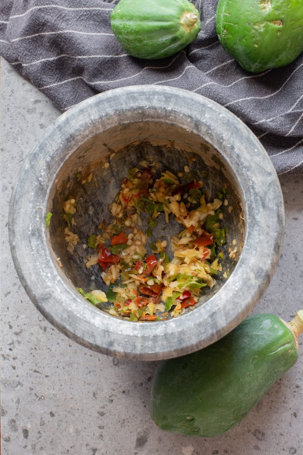 Garlic and Thai chilies pounded into a coarse paste in a mortar.