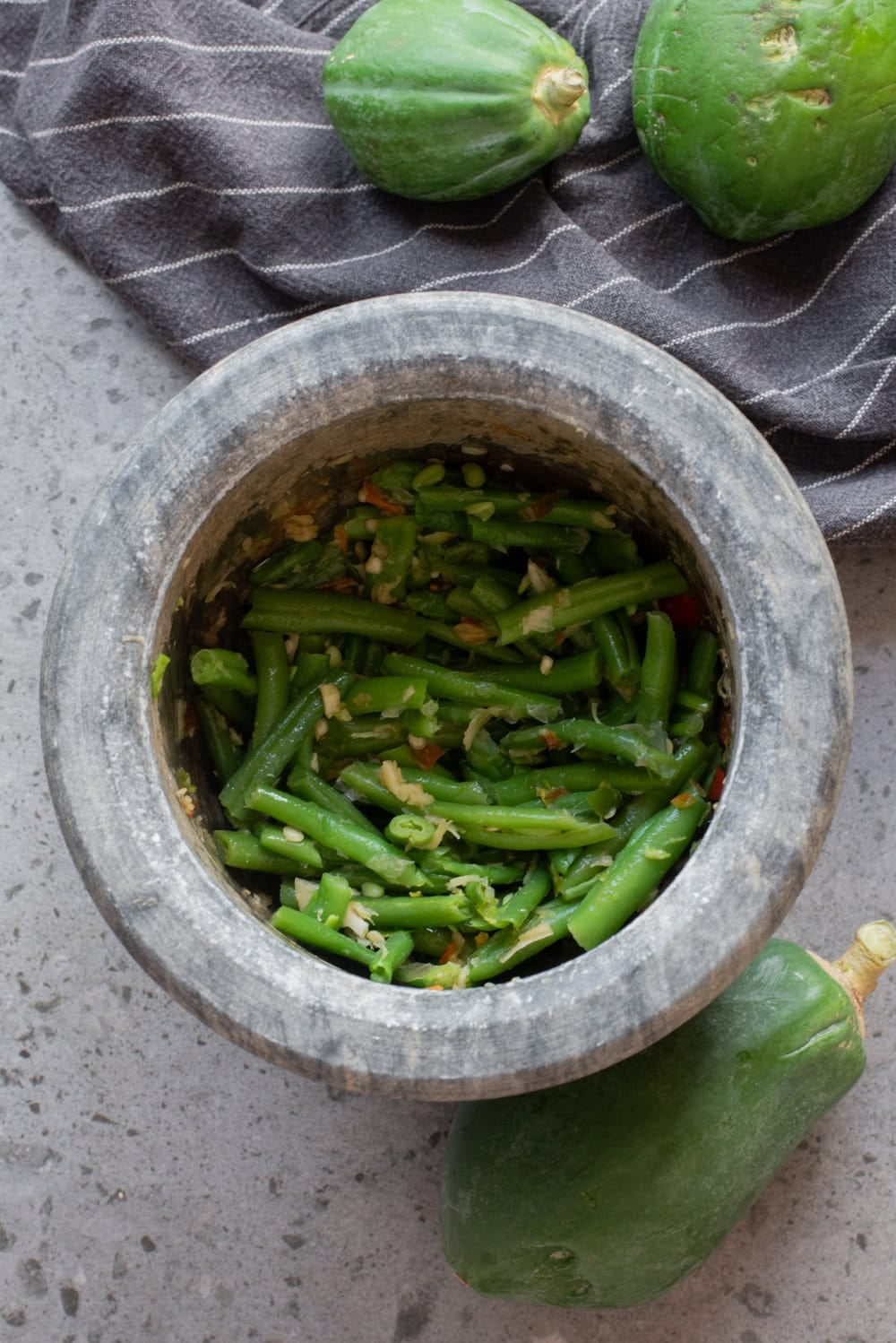 Green beans added to the mortar with the garlic and chili mixture.