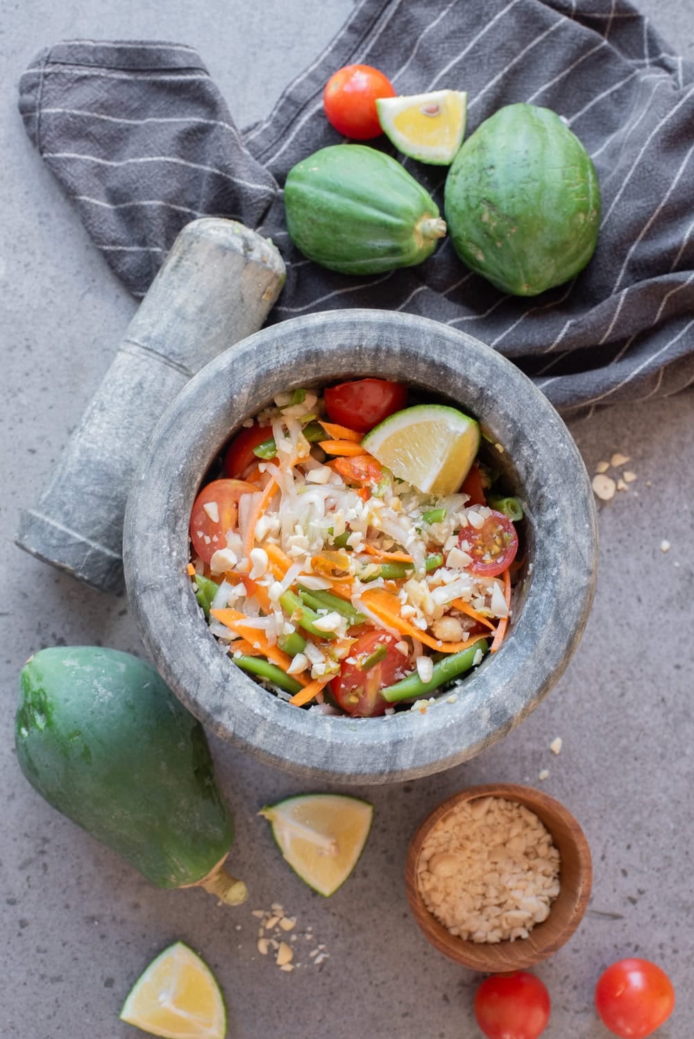 Thai green papaya salad being mixed in a mortar until coated with dressing.