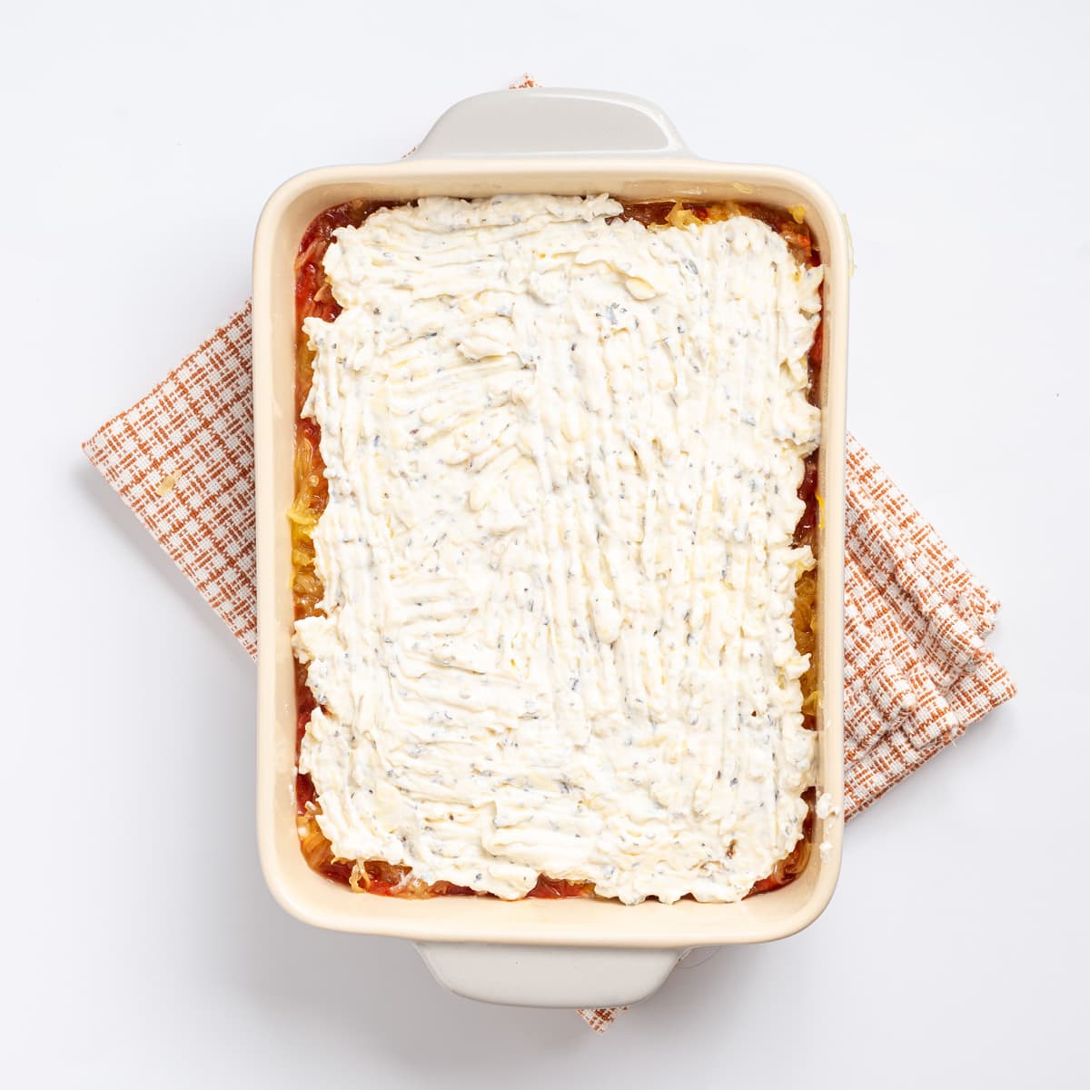 An overhead image of a layer of the ricotta cheese mixture spread on top of the layer of spaghetti squash.